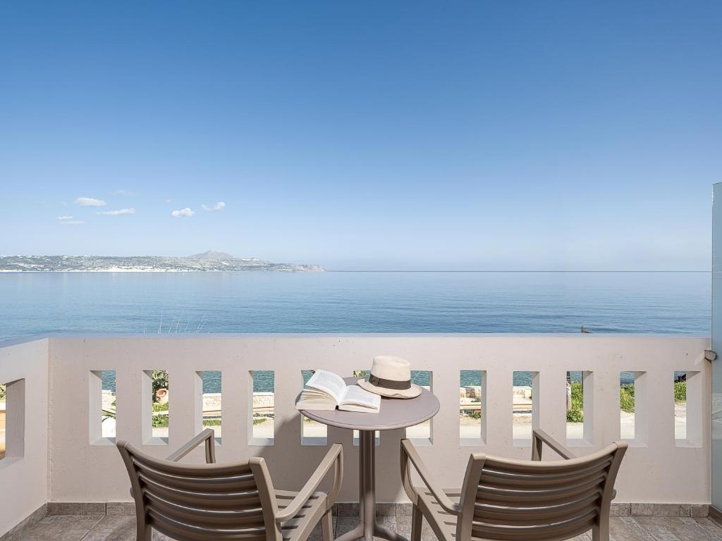 einen Tisch und Stühle auf einem Balkon mit Meerblick in der Unterkunft Porto Kalyves Seaside Aparthotel in Kalyves