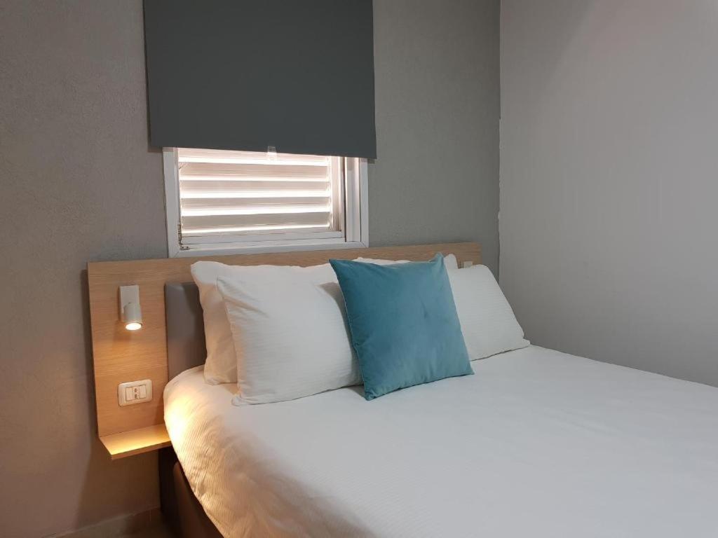 łóżko z niebieską poduszką na górze w obiekcie Airport Guest House w mieście Or Yehuda