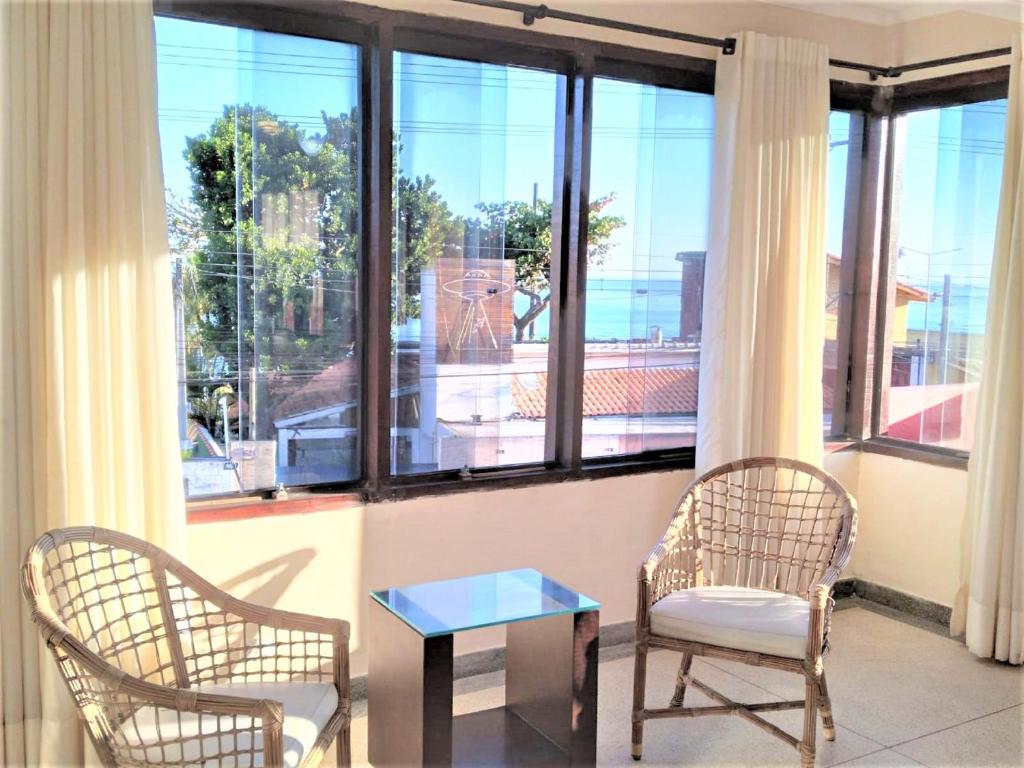 twee stoelen en een tafel voor een groot raam bij Apartamento Vista para o Mar in Maresias