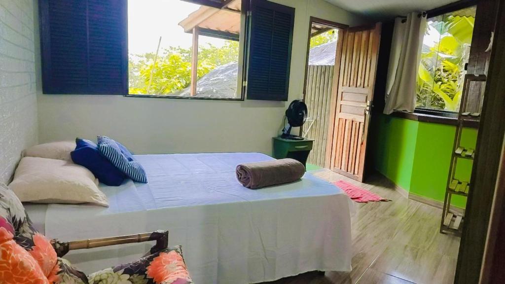 um quarto com uma cama e duas janelas em Chalés da Jack em Angra dos Reis