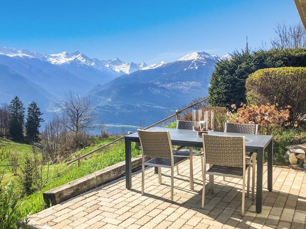 een tafel en stoelen met bergen op de achtergrond bij Mirador Lodge - Crans Montana - Swiss Alps in Crans-Montana