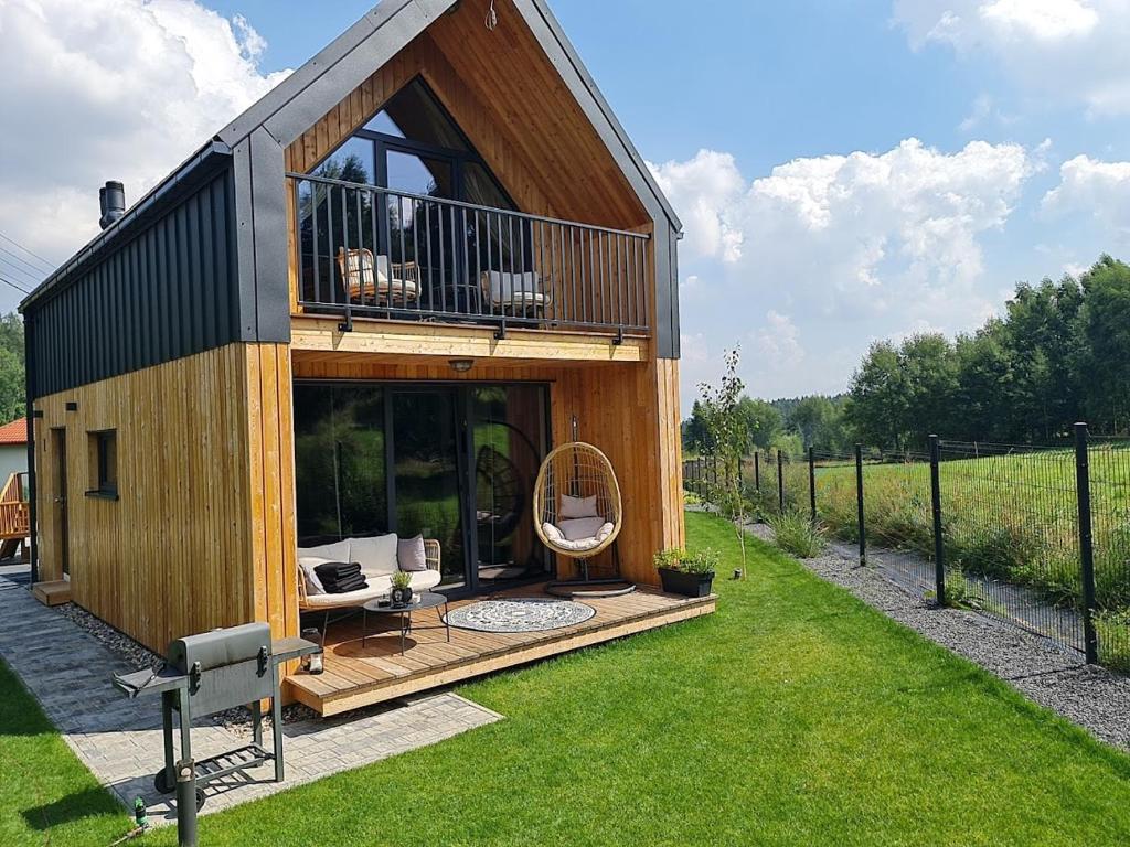 ein kleines Haus mit einer großen Terrasse und einem Spiegel in der Unterkunft Między Brzozami in Szczytna