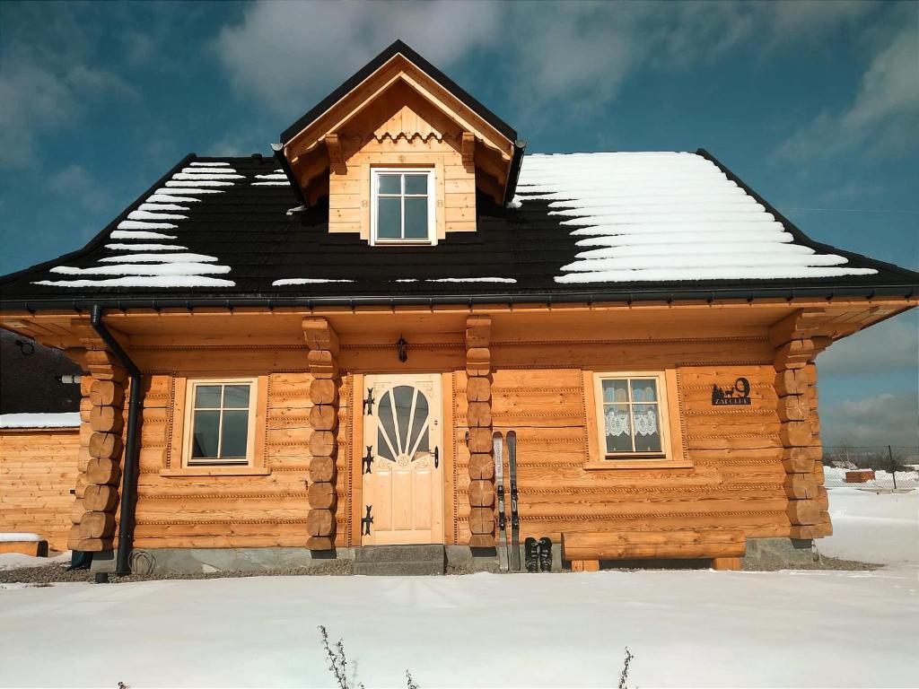 domek z bali i śniegiem na dachu w obiekcie Dom z bala w mieście Lipowa