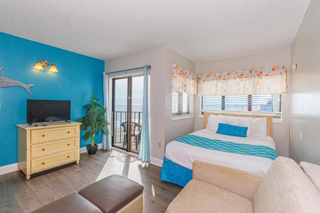 een slaapkamer met een bed en een tv en een bank bij The Palace 505 in Myrtle Beach