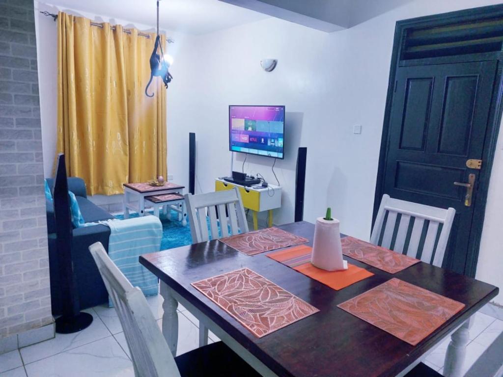a dining room with a table and a television at Lux Suites Milimani Furnished Apartments in Kisumu