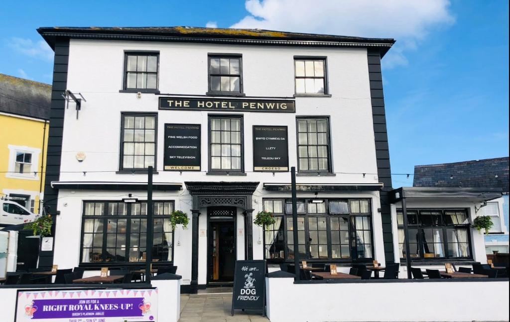 a white building with a sign that reads the hotel tavern at Hotel Penwig in New Quay