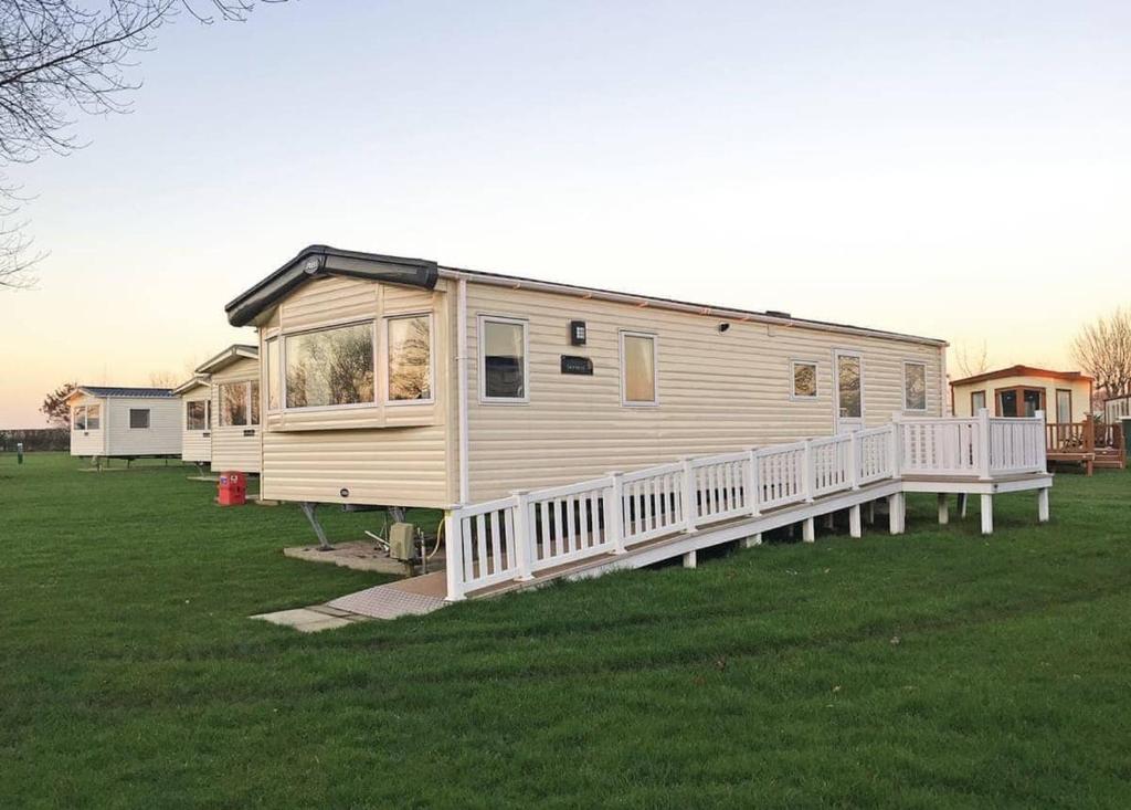 a mobile home with a porch on a grass field at Tollerton Holiday Park in Huby