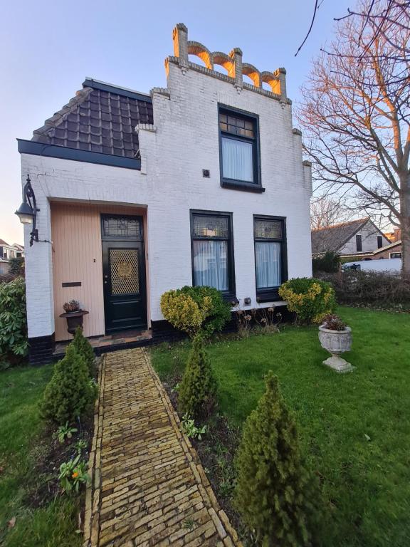 a white house with a brick path in front of it at Klein Middelweg in Uitgeest