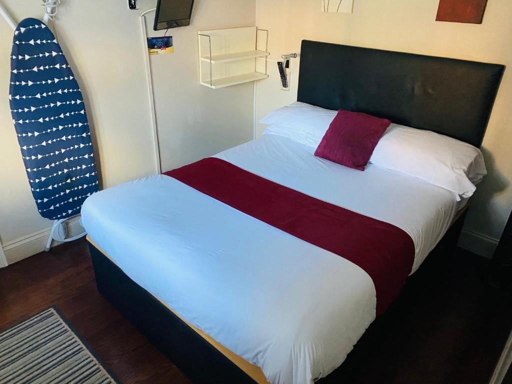 a bedroom with a bed with a red and white blanket at The Railway Sleeper Lodge in Colchester