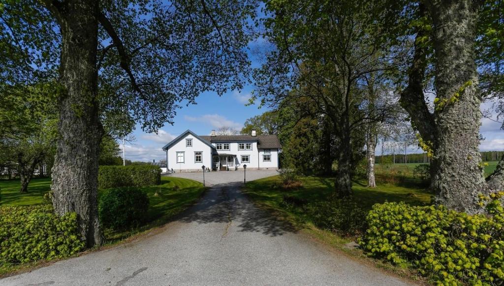 una entrada que conduce a una casa blanca con árboles en HagbackensGård Bed&Breakfast, en Örebro