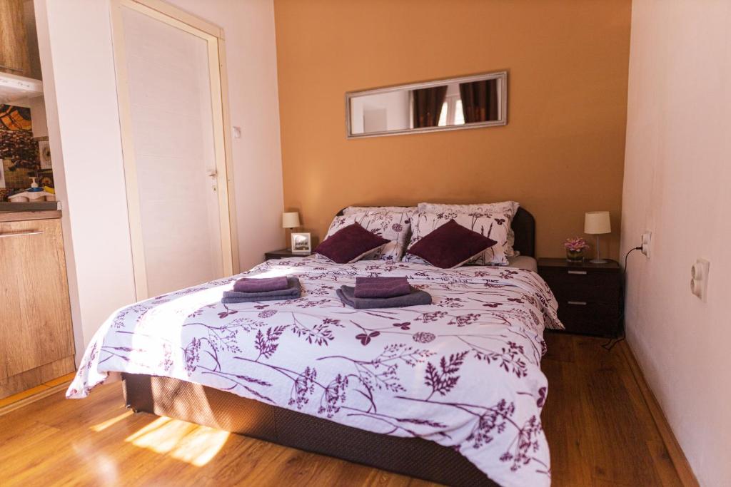 a bedroom with a bed with a purple and white comforter at S&N Apartments Nis in Niš
