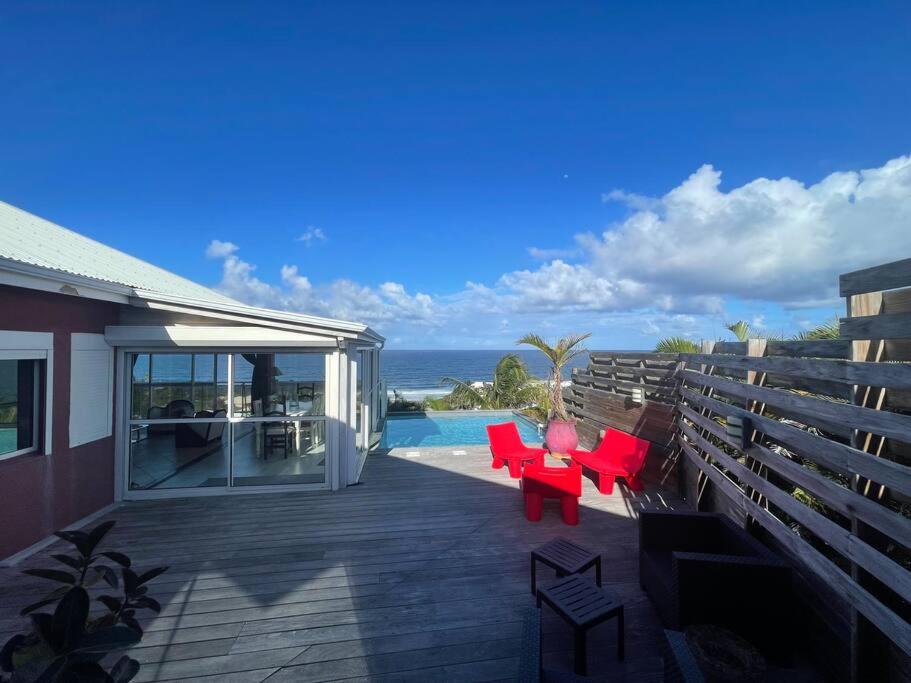 une terrasse avec des chaises rouges et une piscine dans l'établissement Horizon bleu Caraibes, à Le Moule