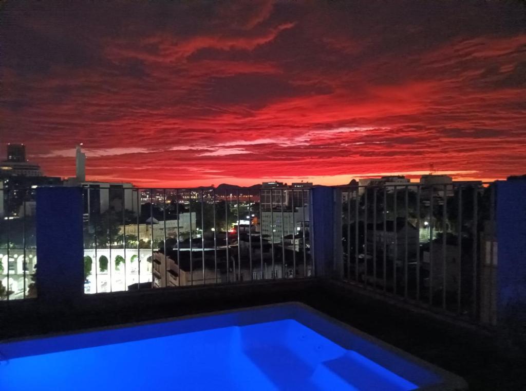 a view of a sunset from a balcony with a swimming pool at Cobertura com Piscina na Lapa in Rio de Janeiro