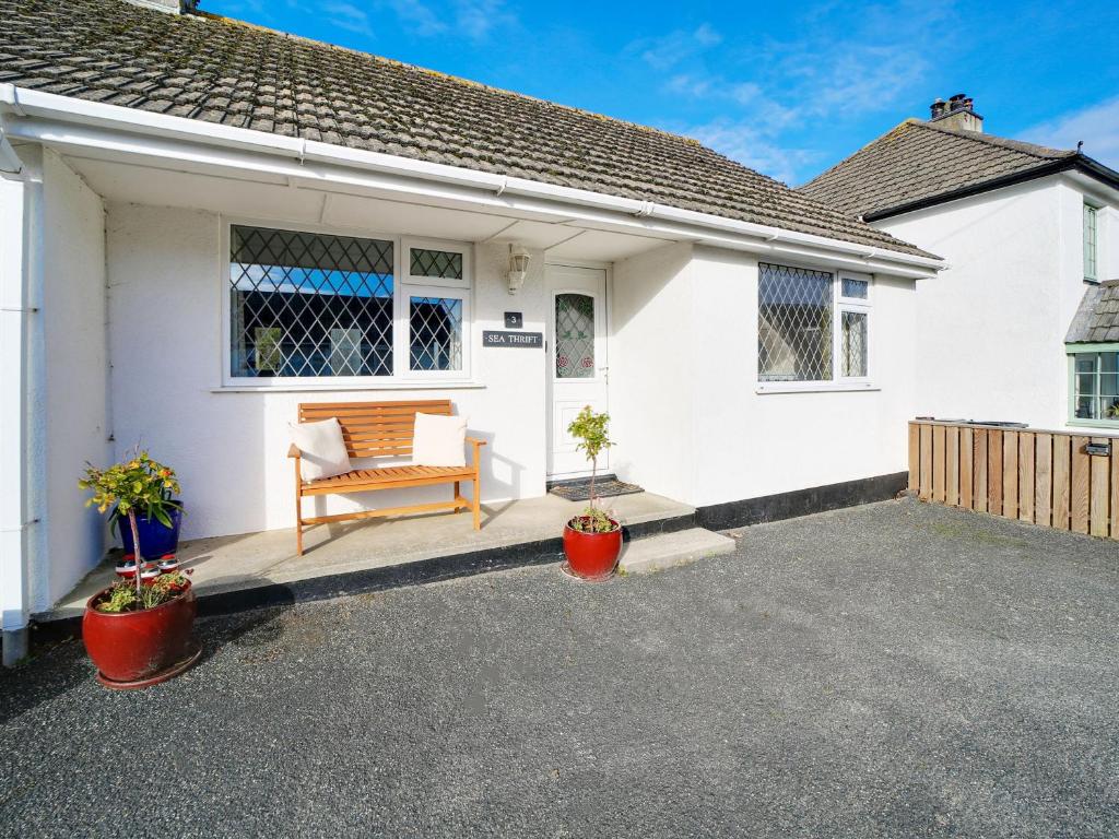 a white house with a bench on a driveway at Sea Thrift in Port Isaac