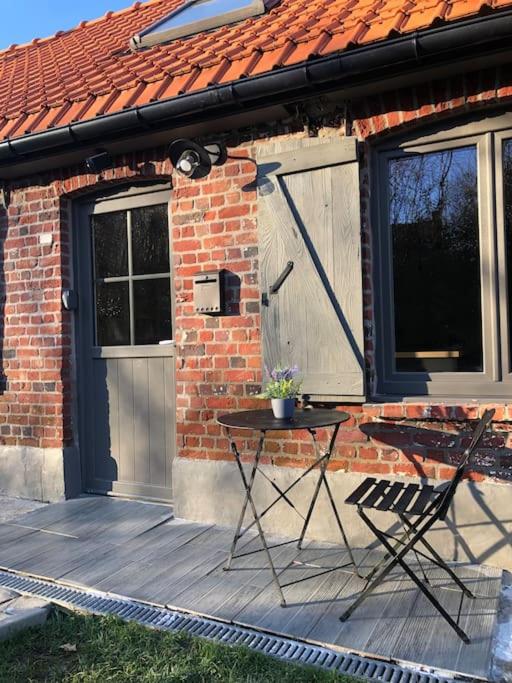 un patio avec une table et des chaises devant une maison dans l'établissement Steen Home : Petite longère de charme, à Boeschèpe