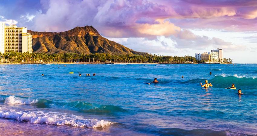 people swimming in the ocean with a mountain in the background at Hawaiian Hospitality in Honolulu
