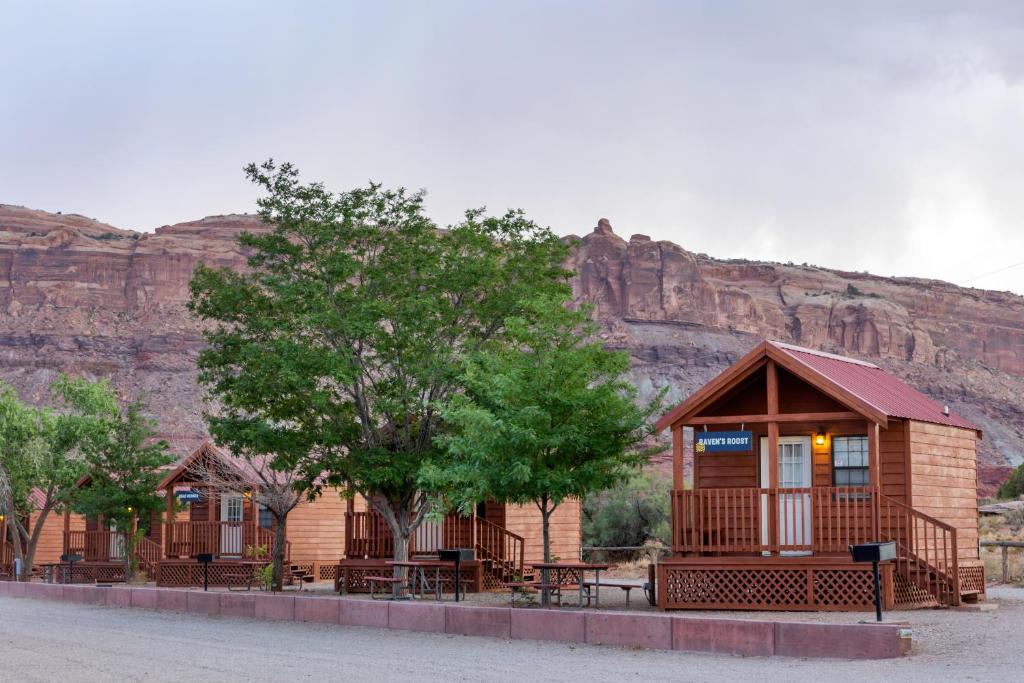 a cabin with tables and trees in front of a mountain at Sun Outdoors Canyonlands Gateway in Moab