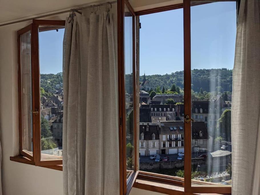 a room with two windows with a view of a city at Maison de quartier populaire. in Aubusson