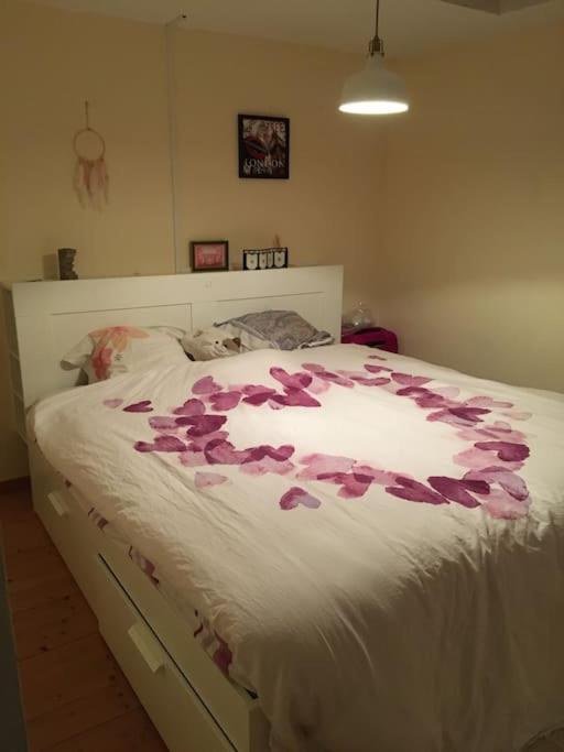 a bed with pink rose petals on it at Maison de quartier populaire. in Aubusson