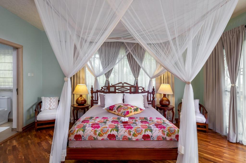 a bedroom with a canopy bed with white curtains at Ewange - A Casa Mia in Kampala