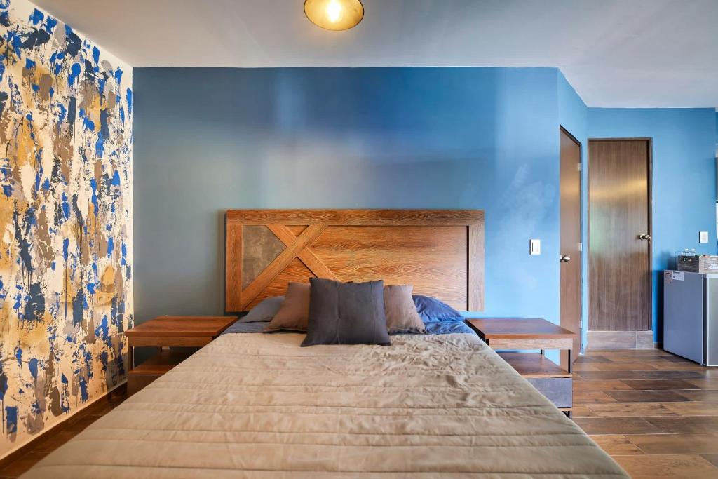 1 dormitorio con 1 cama grande y pared azul en Loft Roma Norte, en Ciudad de México