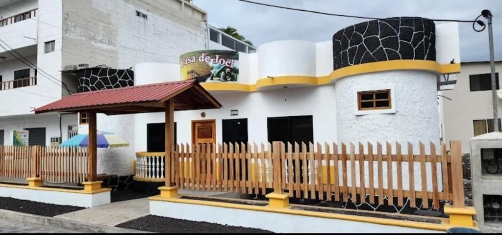 een gebouw met een houten hek ervoor bij La Casa de Joel in Puerto Villamil