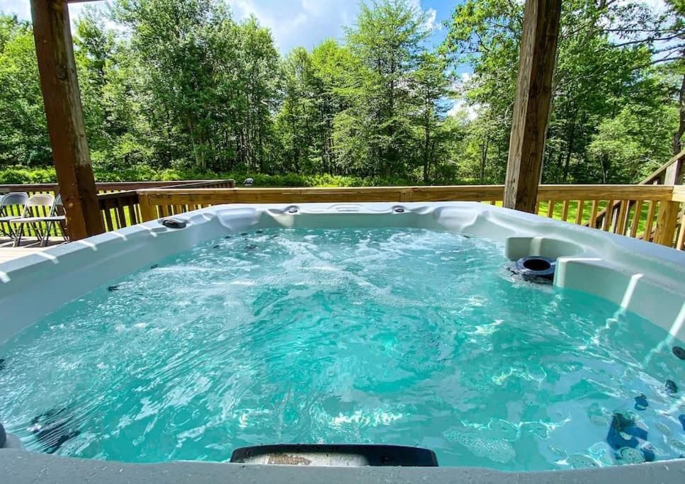 uma banheira de hidromassagem num deque com árvores ao fundo em Secluded 5BR Home~Outdoor hot tub em Long Pond