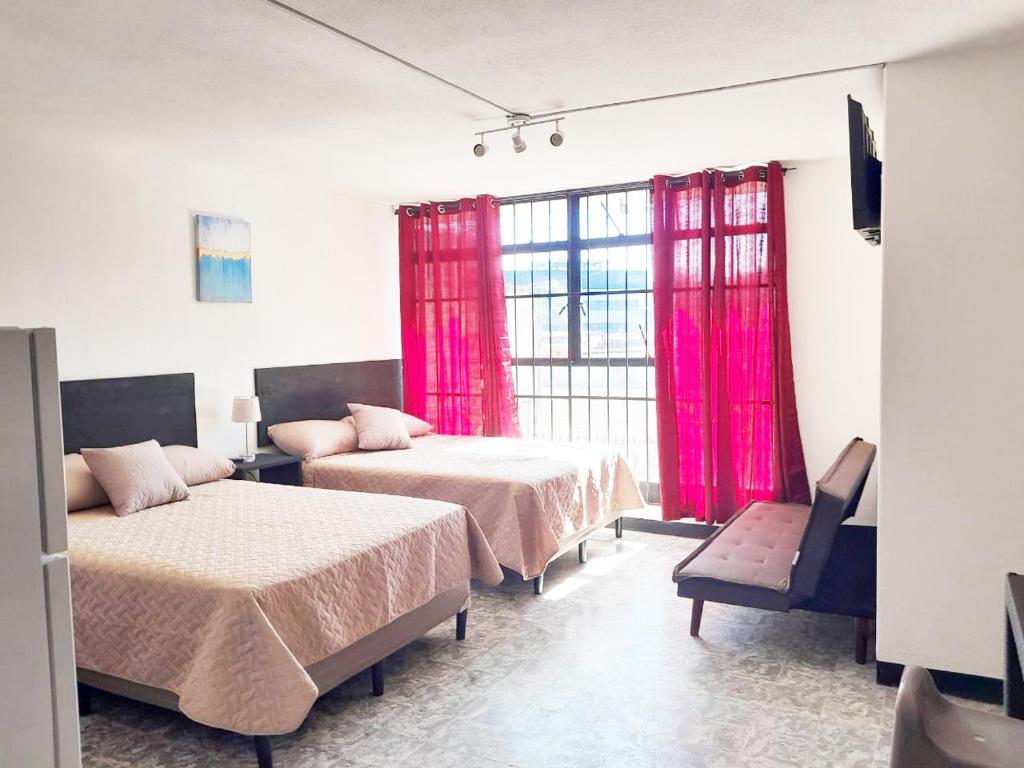 Habitación con 2 camas y ventana con cortinas rosas. en Hospedaje Via 7 en Guatemala