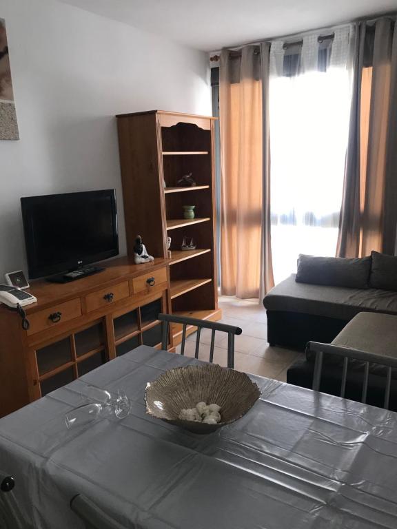 sala de estar con mesa, TV y sofá en Apartamento “El Callao” en Puerto del Rosario