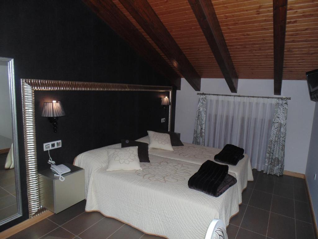 a bedroom with two beds with white sheets and black pillows at Hotel Ribera de Langa in Langa de Duero