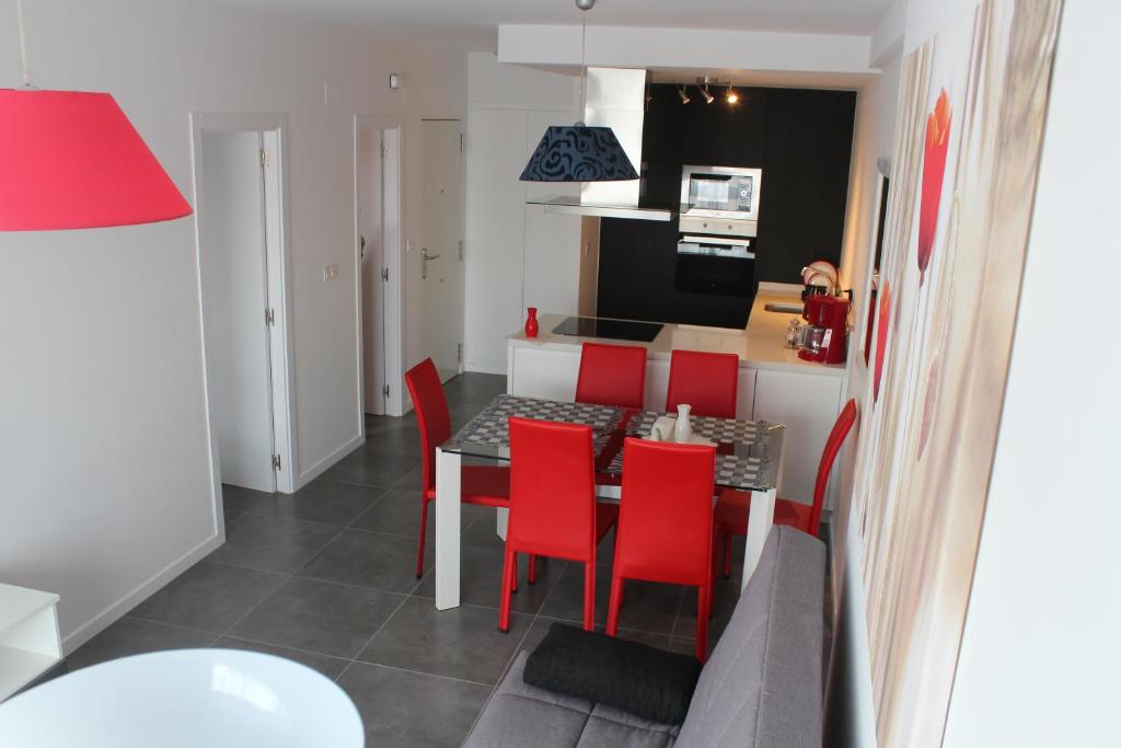 een keuken en eetkamer met een tafel en rode stoelen bij New apartment with sea view of Andrew and Natallia in Campoamor