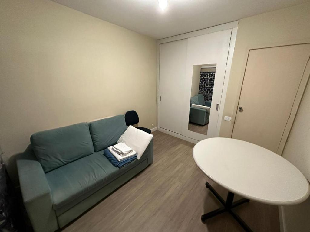 ein Wohnzimmer mit einem blauen Sofa und einem Tisch in der Unterkunft Quarto Aconchegante in Rio de Janeiro