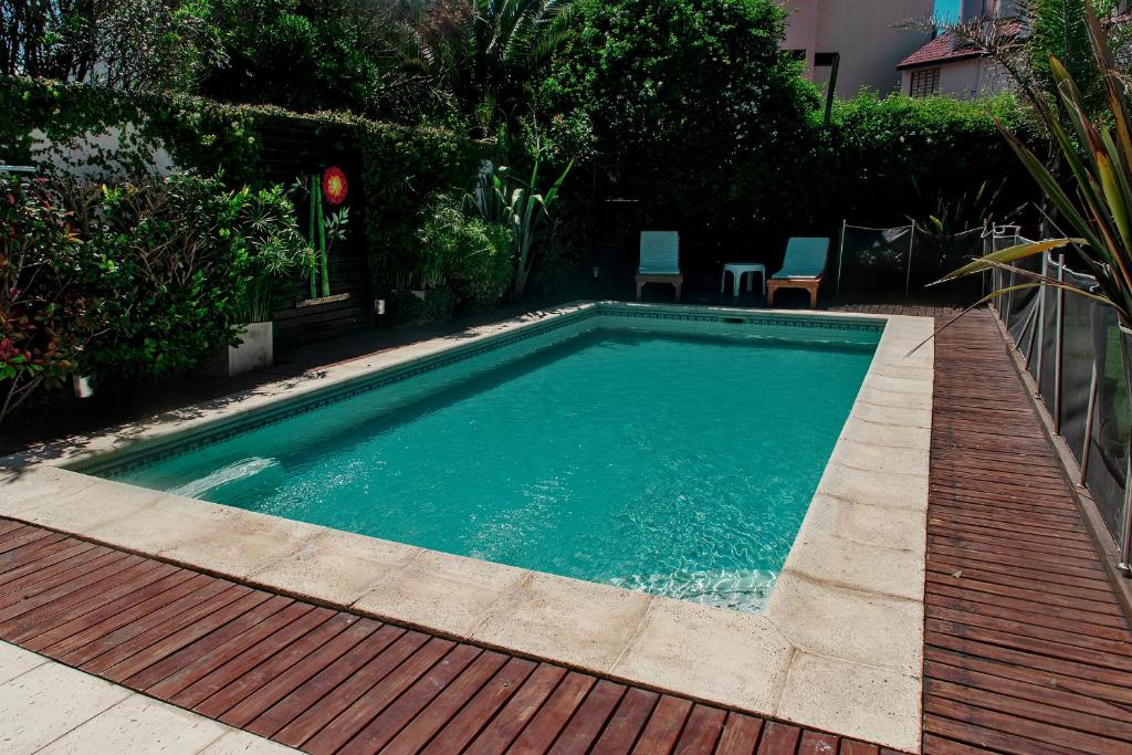 a swimming pool in a yard with a wooden deck at Alma Natura in Villa Gesell