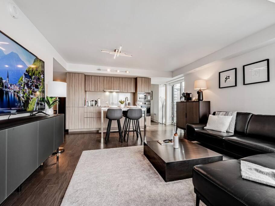 a living room with a black couch and a kitchen at Luxury Condo on Bay Street in Toronto