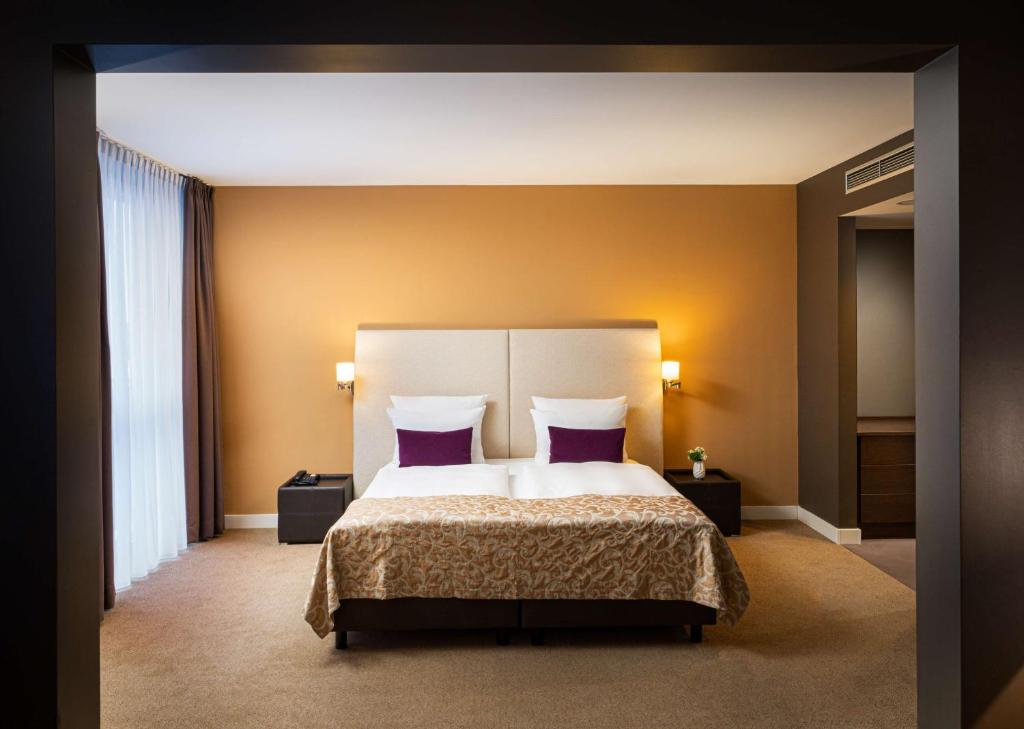 ein Schlafzimmer mit einem großen Bett mit lila Kissen in der Unterkunft The Rilano Hotel München in München