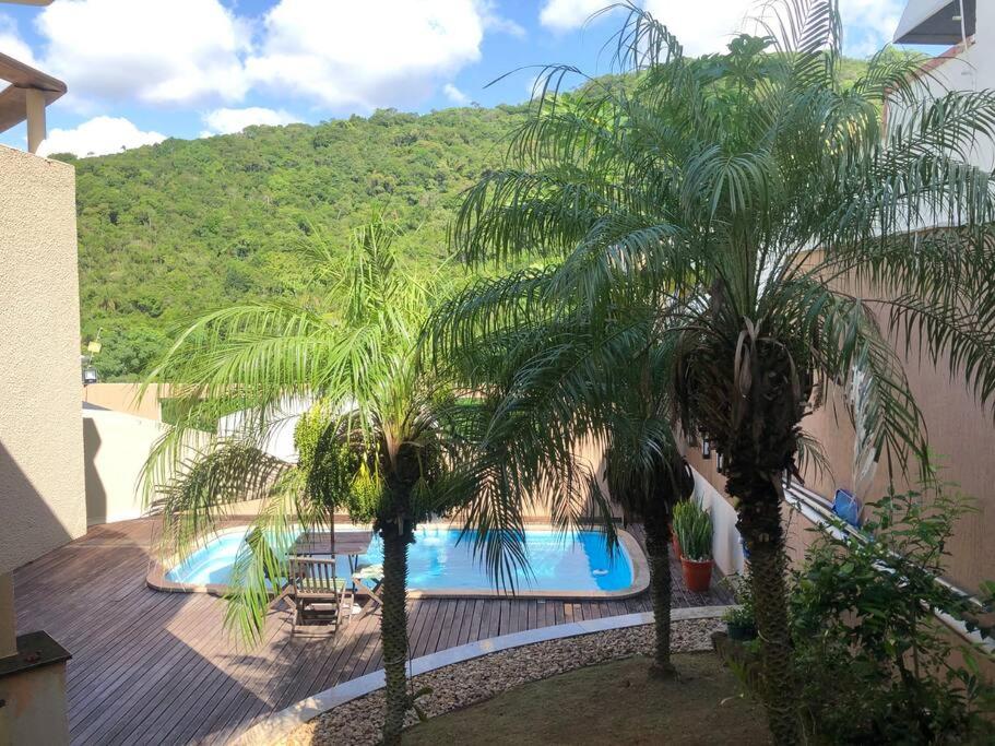 vistas a una piscina con 2 palmeras en Linda casa com piscina, en Balneário Camboriú