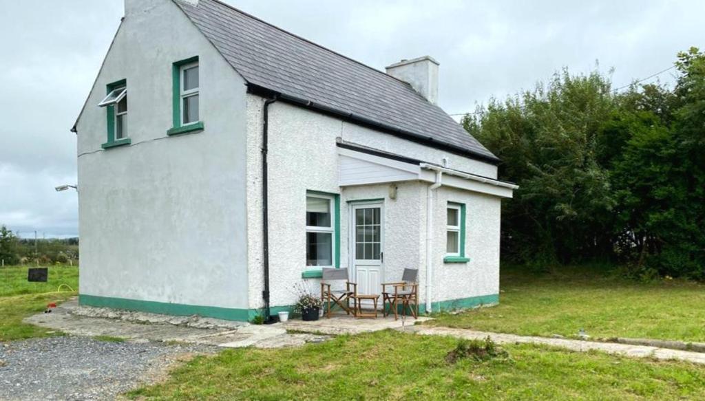 a small white house with a table and chairs outside at Traditional 3-Bed Cottage sea mountain views in Falcarragh