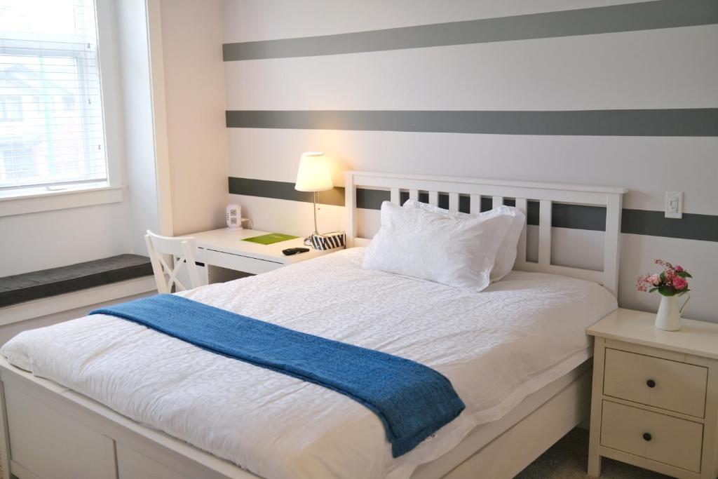 um quarto com uma cama com uma parede listrada em azul e branco em Vancouver West Cozy Retreat by Host Launch em Vancouver