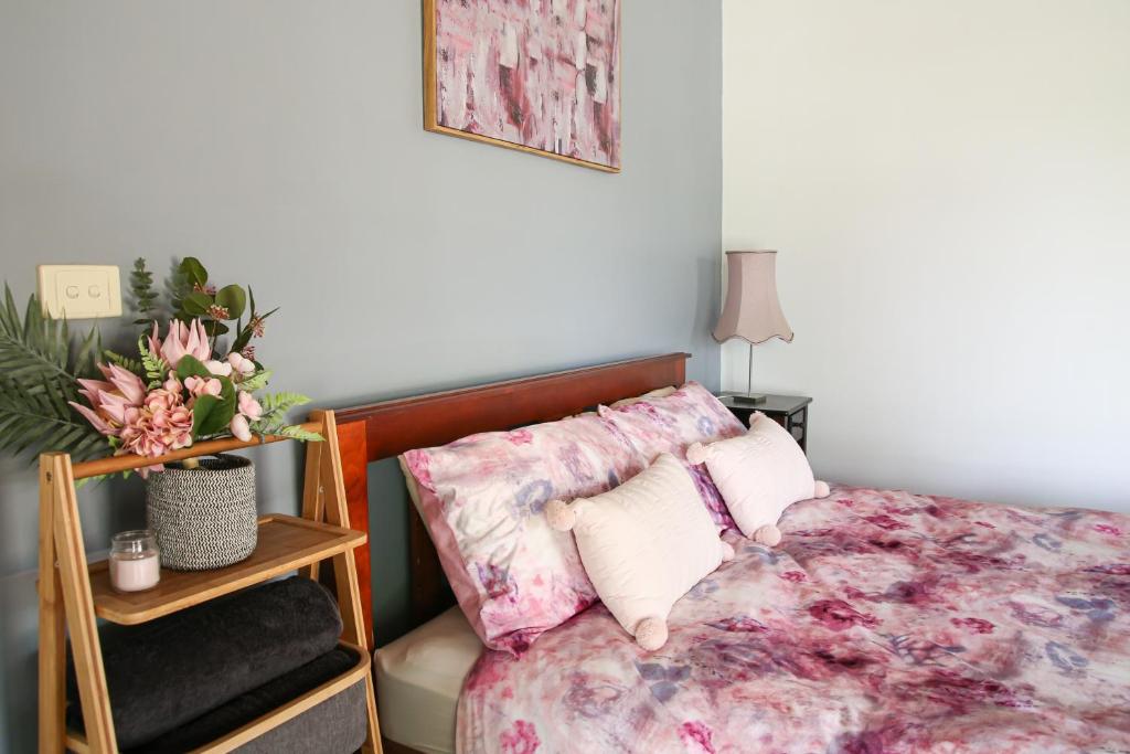 a bedroom with a bed with pink floral sheets at Jardine Lodge - Can sleep 22! in Corryong
