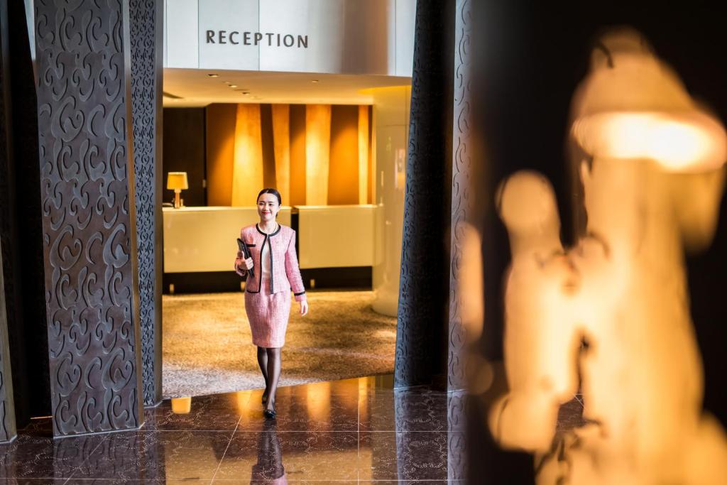 a woman walking down a hallway in a hotel lobby at The Langham, Shanghai, Xintiandi in Shanghai