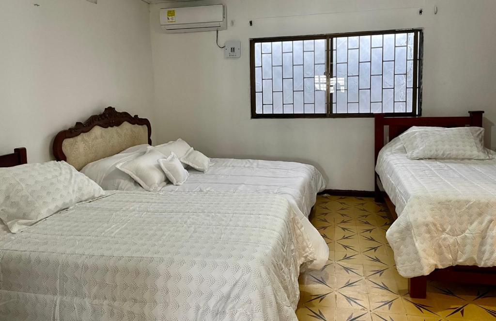 1 dormitorio con 2 camas y ventana en La Casa de Tía Ana, en Ríohacha