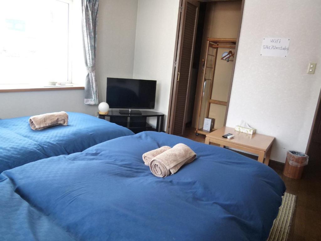 Dos camas azules en una habitación con toallas. en Otaru - House / Vacation STAY 57190 en Otaru
