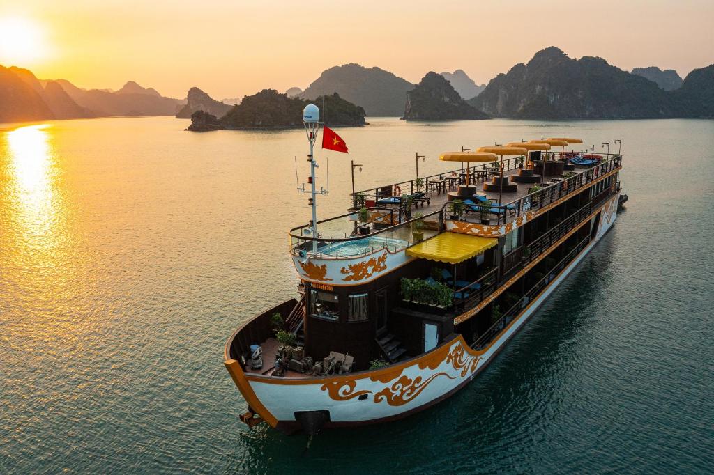 Nostalgia Halong Cruise في ها لونغ: قارب عبارة في الماء عند غروب الشمس