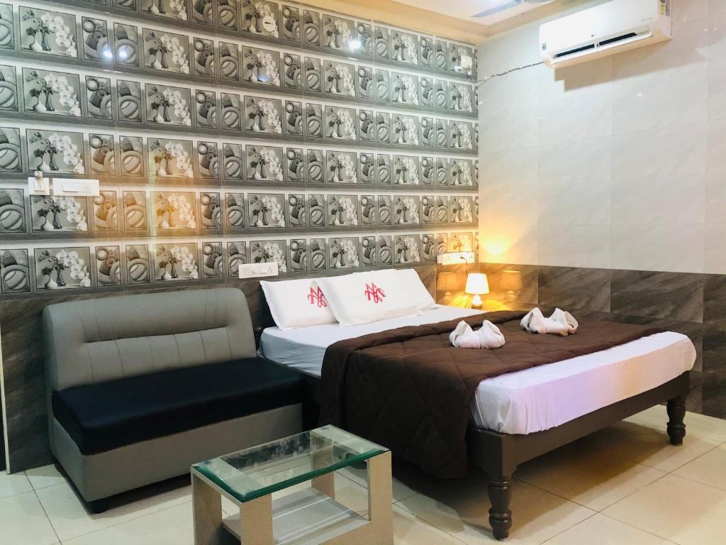 a bedroom with two beds and a couch and a wall with plates at MARINA PALACE in Chennai