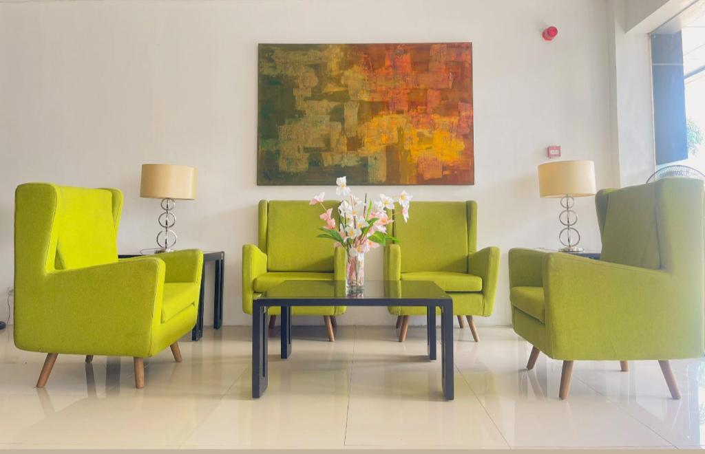 una sala de estar con sillas verdes y una mesa con flores en TOP STAR HOTEL OTON en Oton