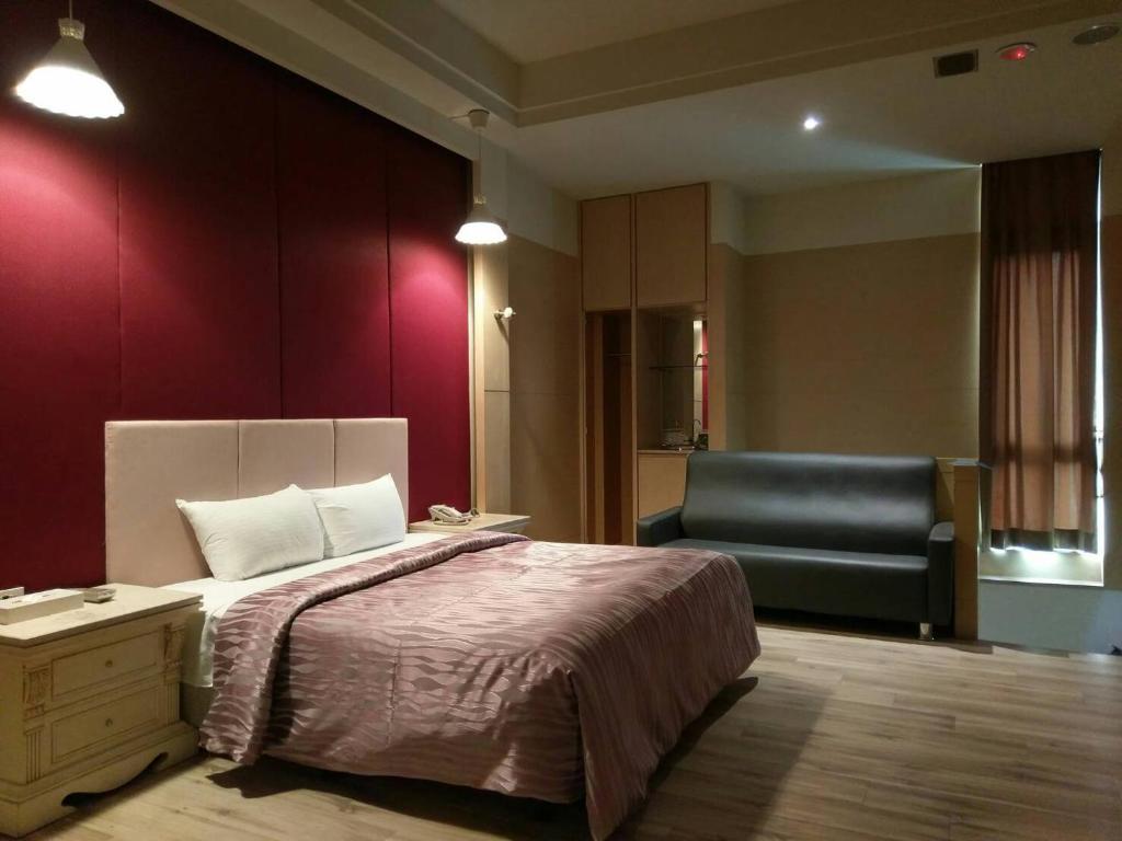 um quarto de hotel com uma cama e uma cadeira em 金利星精品旅館 em Nan-p'ing