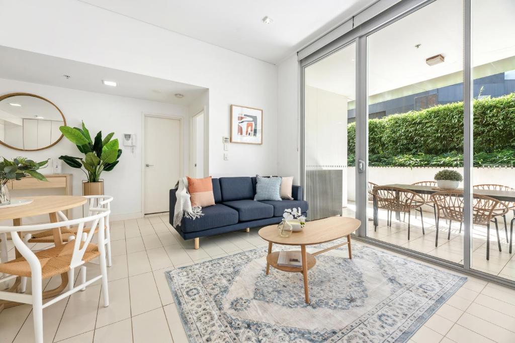 a living room with a blue couch and a table at The Alta Apartments by Urban Rest in Sydney