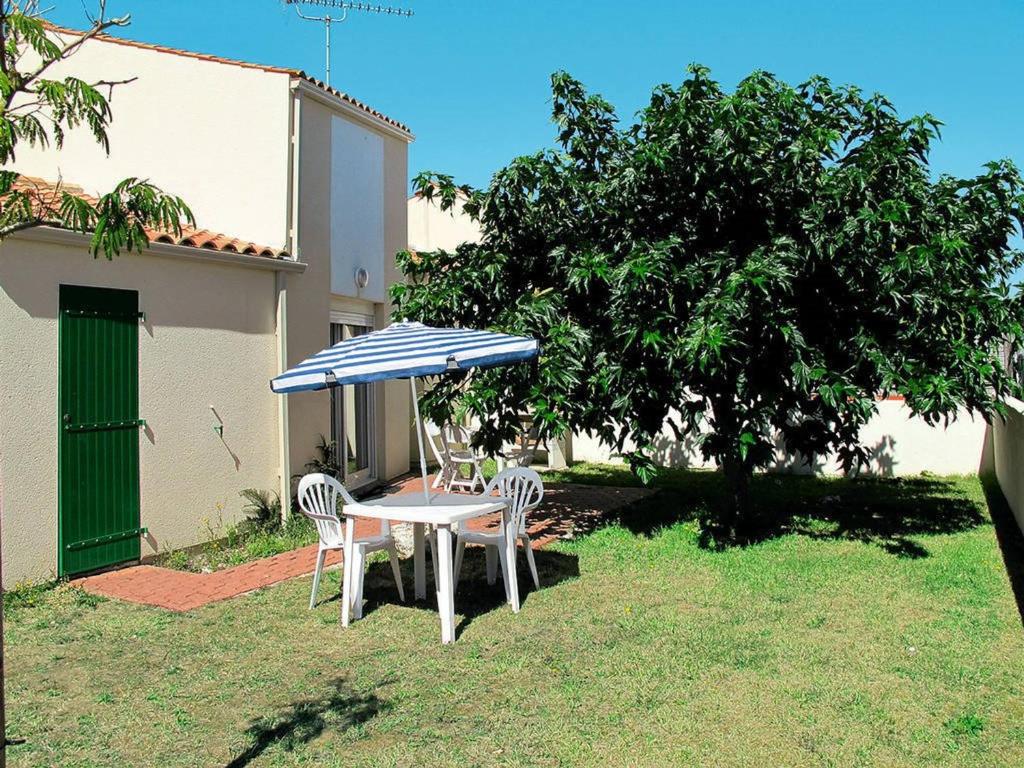 einen Tisch und Stühle unter einem blauen und weißen Schirm in der Unterkunft Maison 6 couchages près de la plage à Saint-Denis-d'Oléron - FR-1-246A-196 in Saint-Denis-dʼOléron