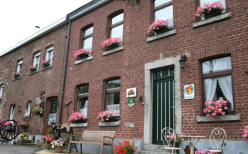 um edifício de tijolos vermelhos com flores nas janelas em B&B Ferme du Petit Breuil em Verviers