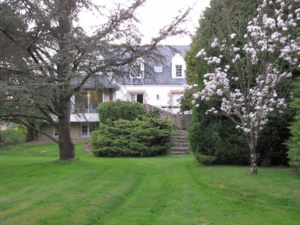 a white house with a tree with white flowers at Gîte Brocéliande in Baulon